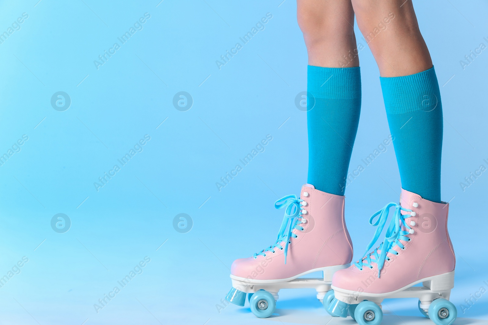 Photo of Woman with vintage roller skates on color background, closeup. Space for text