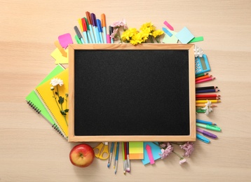 Blackboard, stationery, apple and flowers on wooden table, flat lay with space for text. Teacher's Day