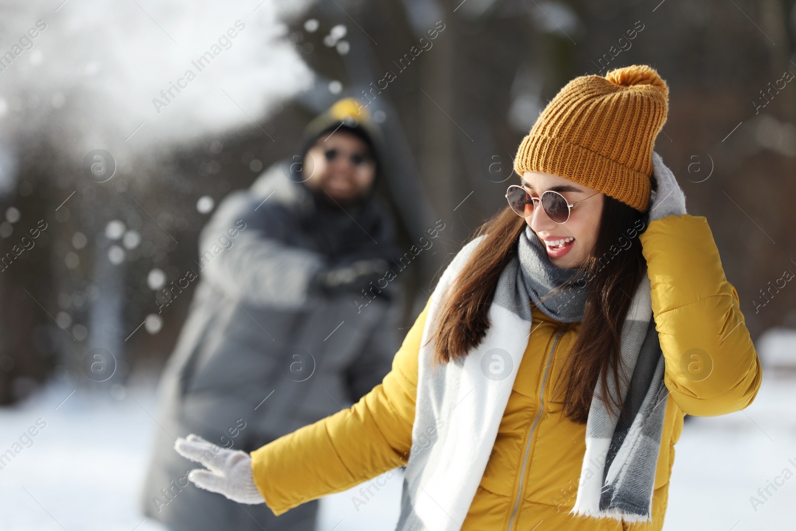 Photo of Happy couple playing snowballs on winter day outdoors