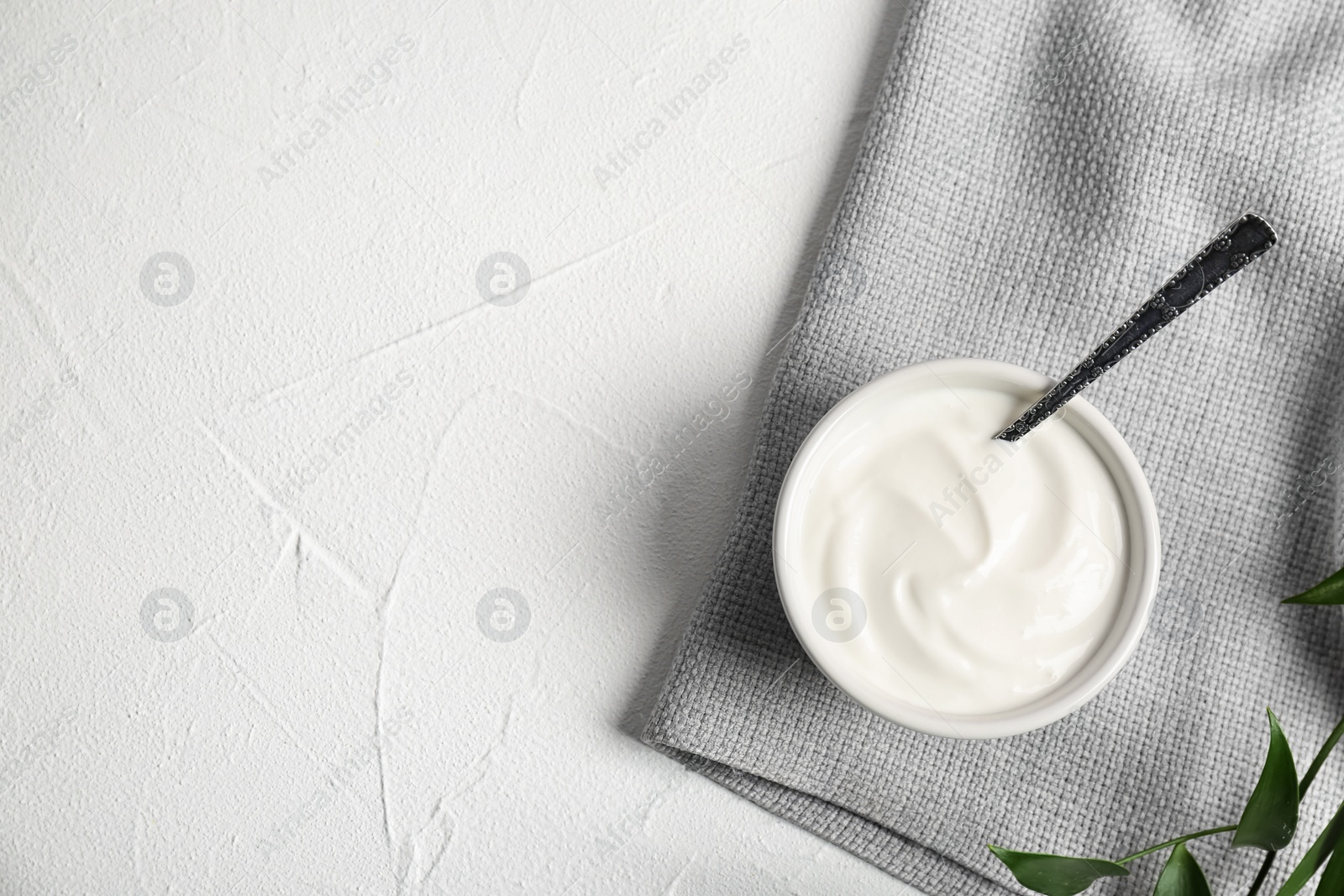 Photo of Bowl and spoon with yummy yogurt on table