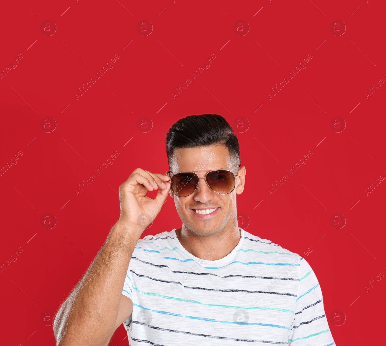 Photo of Handsome man wearing sunglasses on red background