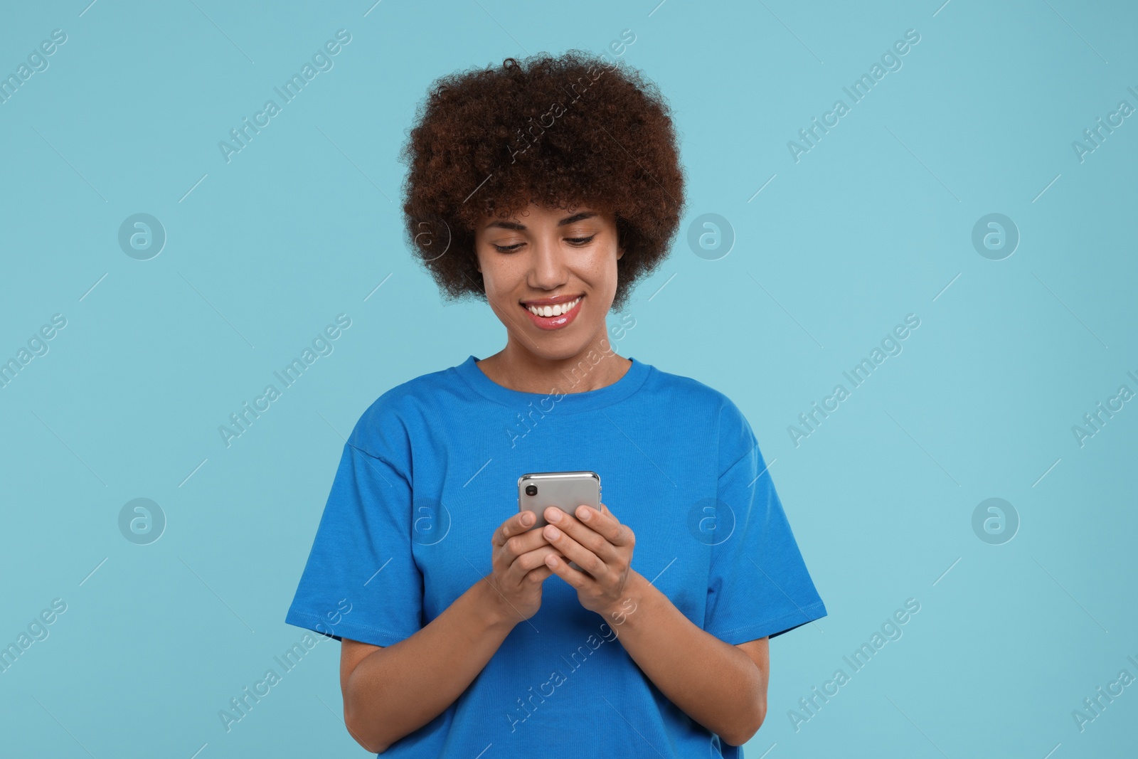 Photo of Happy young woman with smartphone on light blue background