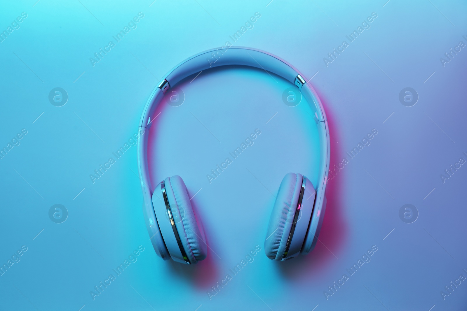 Photo of Stylish modern headphones with earmuffs on color background, top view