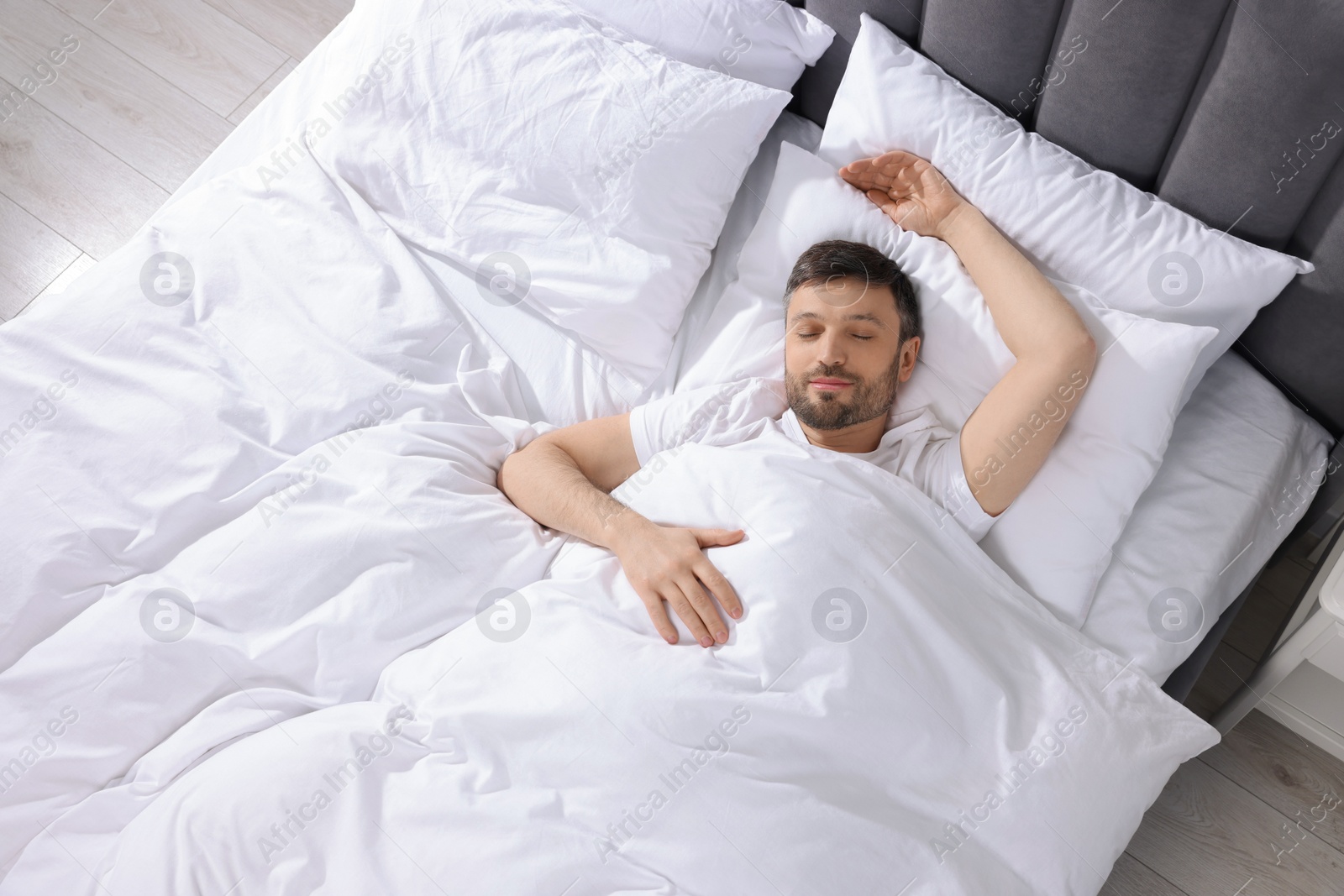 Photo of Handsome man sleeping in soft bed at home, top view