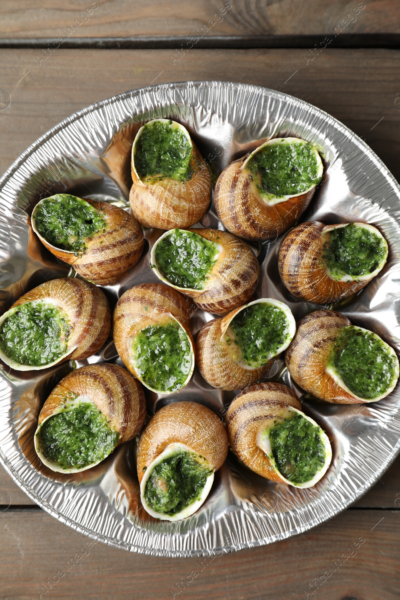 Photo of Delicious cooked snails on wooden table, top view