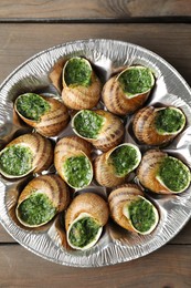 Photo of Delicious cooked snails on wooden table, top view