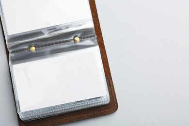 Leather business card holder with blank cards on light grey background, top view. Space for text