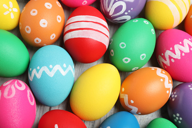 Photo of Many bright Easter eggs on wooden background, above view