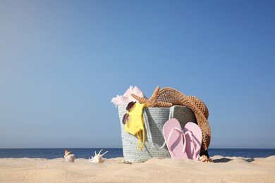 Bag and beach accessories on sand near sea