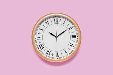 Photo of Stylish round clock on pale pink background, top view. Interior element