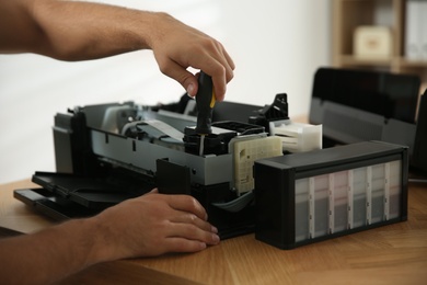 Photo of Repairman with screwdriver fixing modern printer, closeup