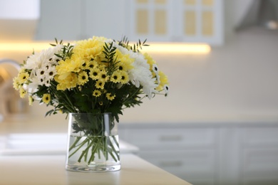 Photo of Vase with beautiful chrysanthemum flowers on countertop in kitchen, space for text. Interior design