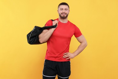 Handsome man with sports bag on yellow background, space for text