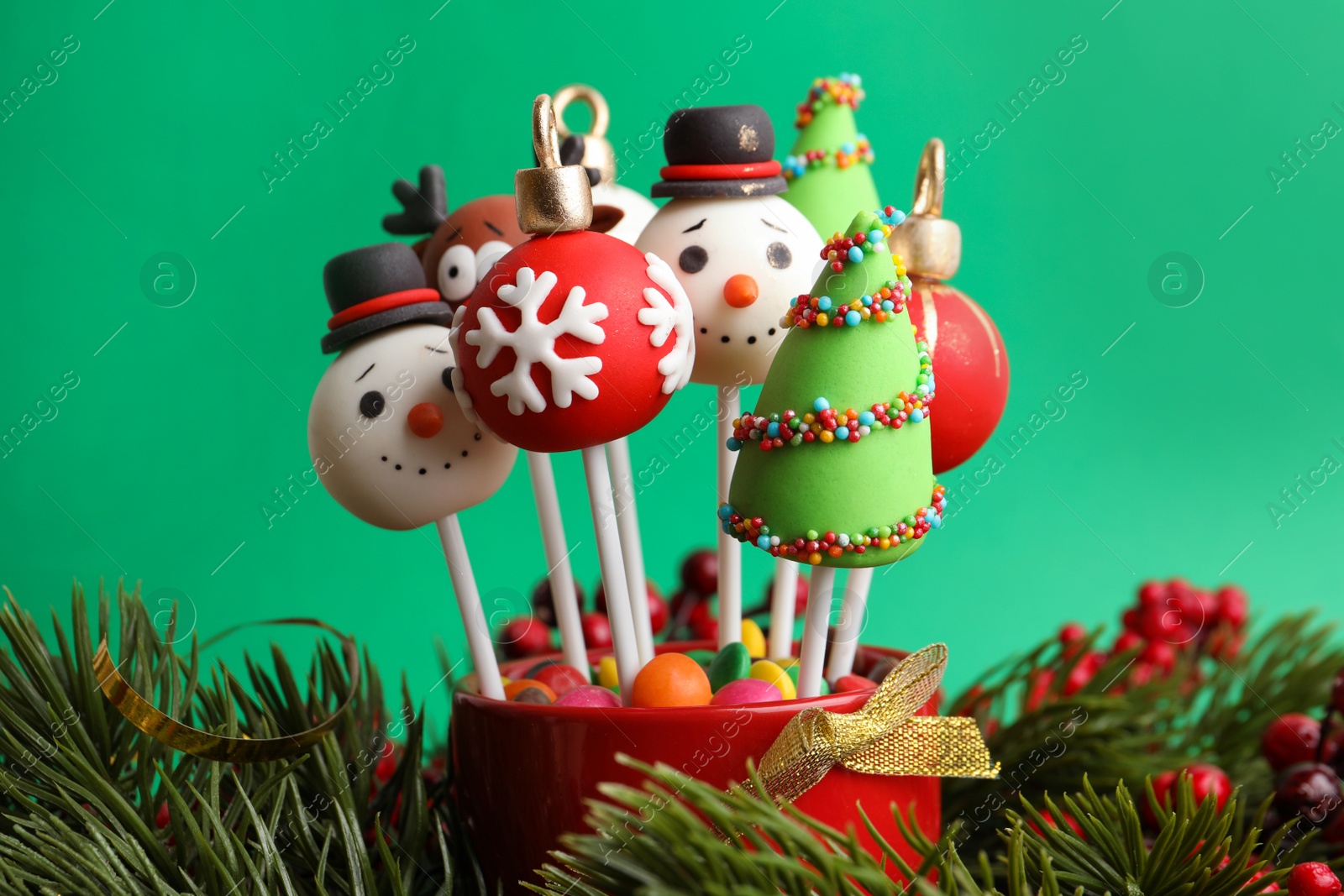 Photo of Delicious Christmas themed cake pops on green background, closeup