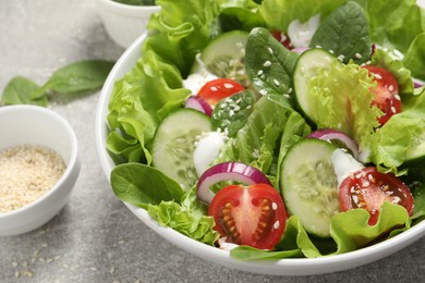 Delicious salad in bowl on light grey table, closeup