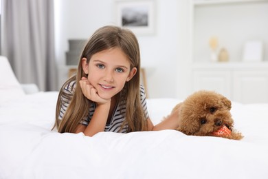 Little child and cute puppy on bed at home. Lovely pet