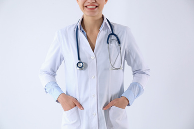Young doctor with stethoscope on white background, closeup
