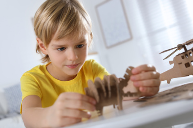 Photo of Little boy making carton toys at table indoors. Creative hobby