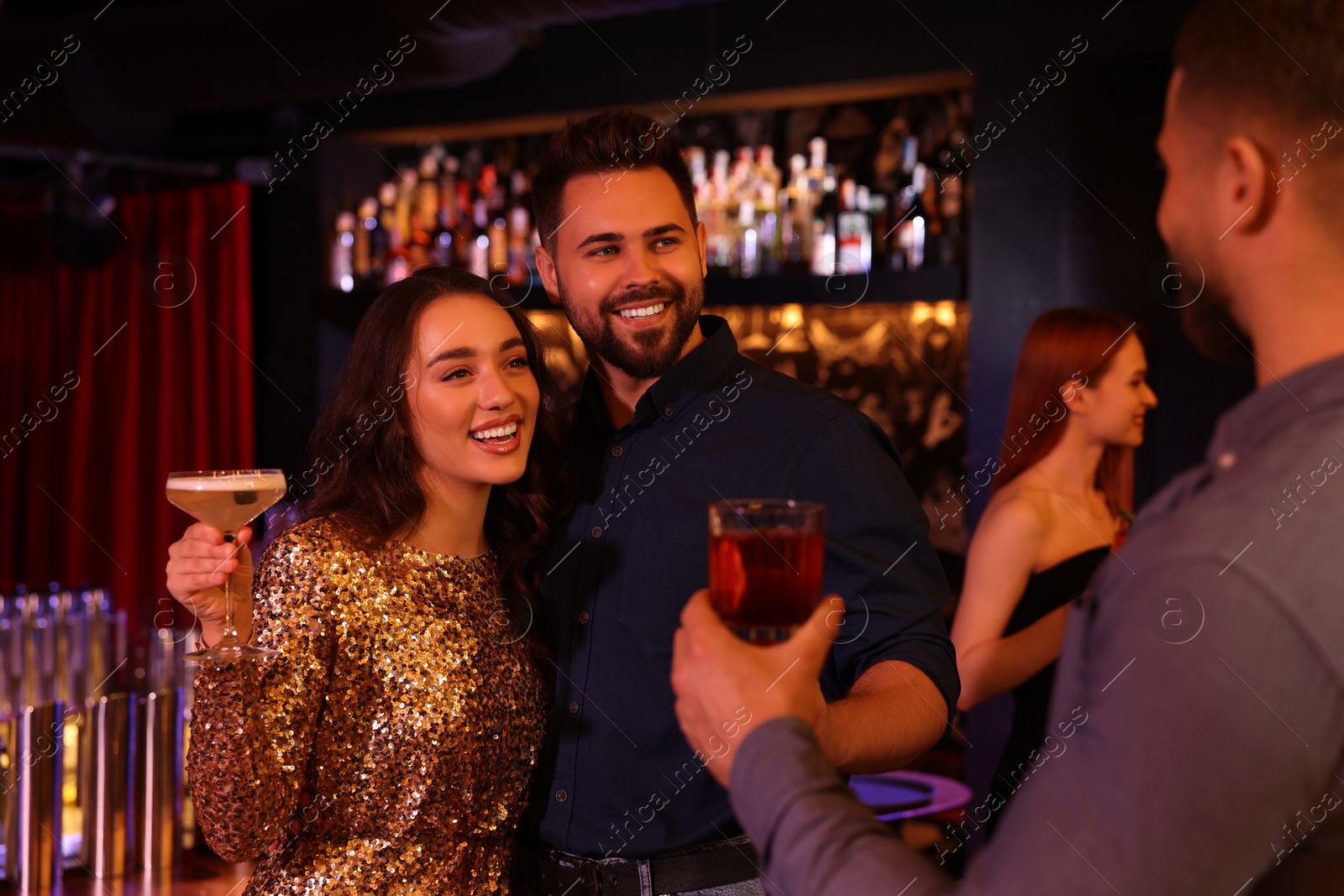 Photo of Happy friends with cocktails spending time together in bar