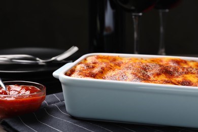 Photo of Tasty cooked lasagna in baking dish on table, closeup