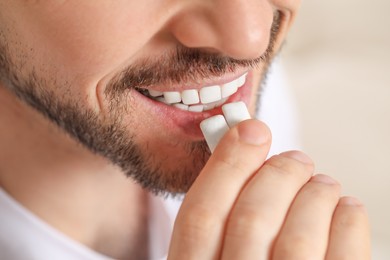 Man putting chewing gums into mouth on blurred background, closeup