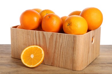 Fresh oranges in crate on wooden table against white background