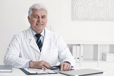 Portrait of senior doctor in white coat at workplace