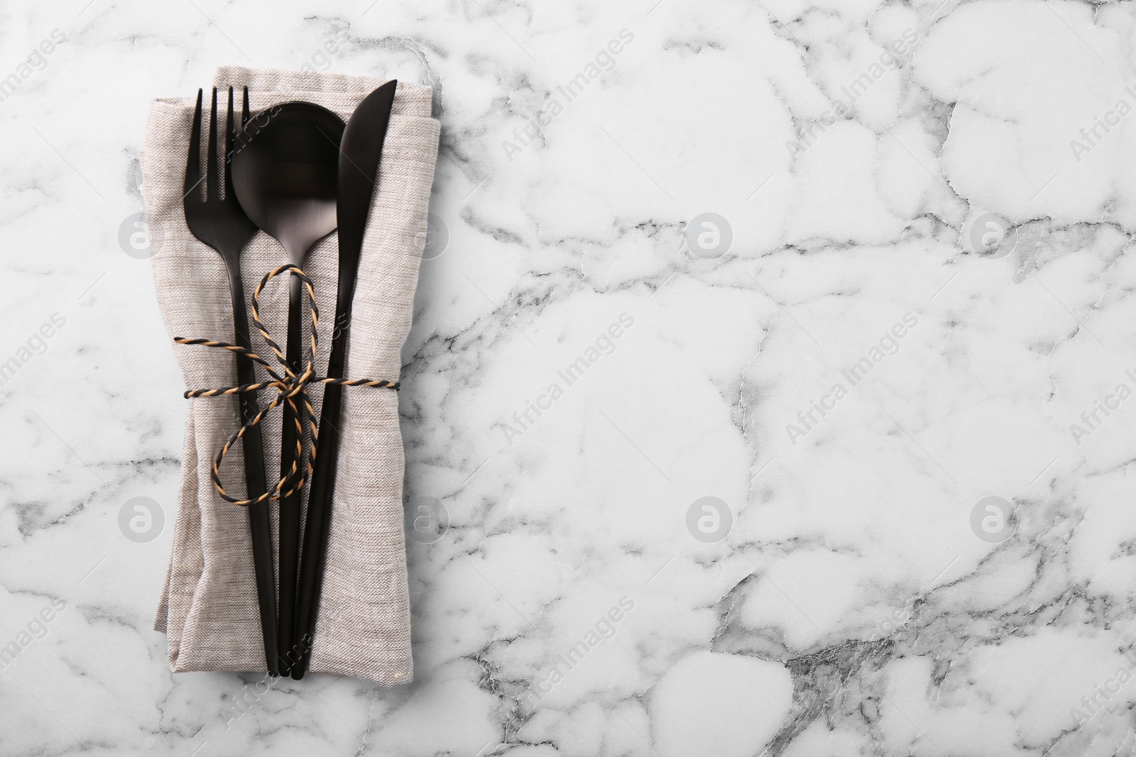 Photo of Set of stylish cutlery and napkin on white marble table, top view. Space for text