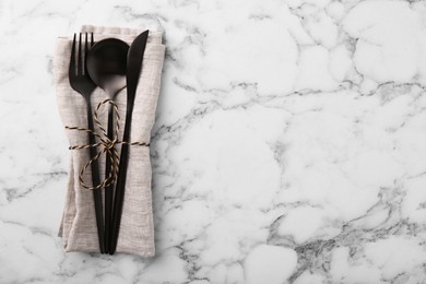 Set of stylish cutlery and napkin on white marble table, top view. Space for text