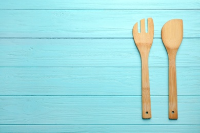 Wooden spatula and fork on color background, top view with space for text