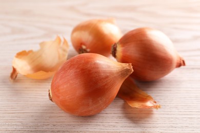 Photo of Raw ripe onions and husk on wooden table