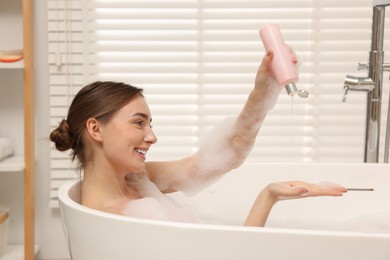 Photo of Woman pouring shower gel onto hand in bath indoors