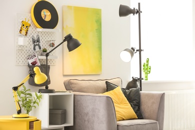 Photo of Room interior with modern lamps and comfortable armchair