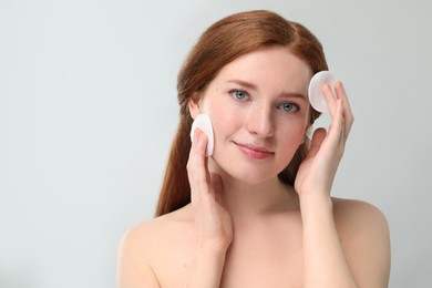 Photo of Beautiful woman with freckles wiping face on grey background. Space for text