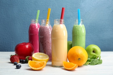 Photo of Bottles with healthy detox smoothies and ingredients on table