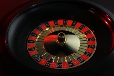 Photo of Roulette wheel with ball on black table, closeup. Casino game