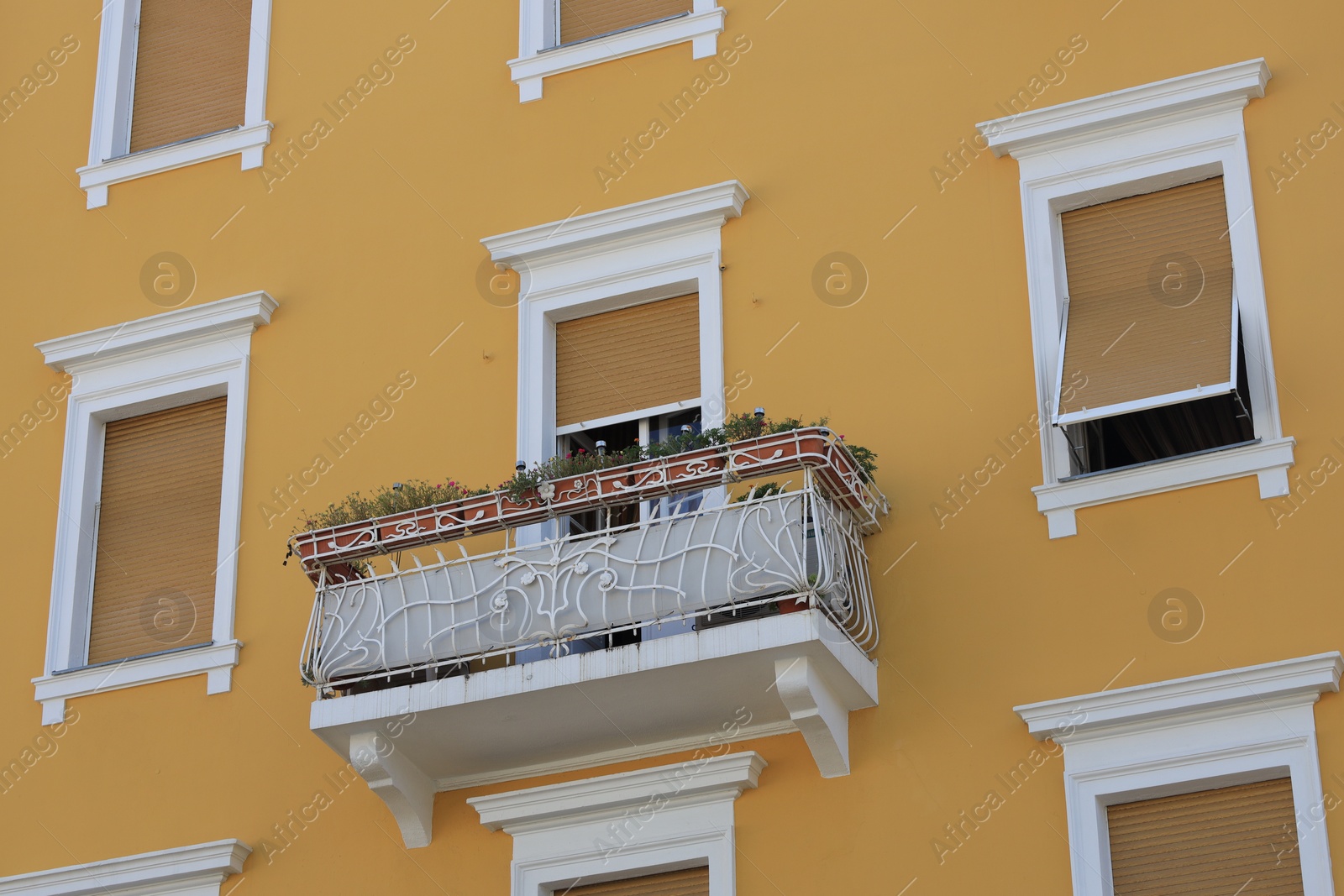 Photo of View of beautiful yellow building with balcony outdoors