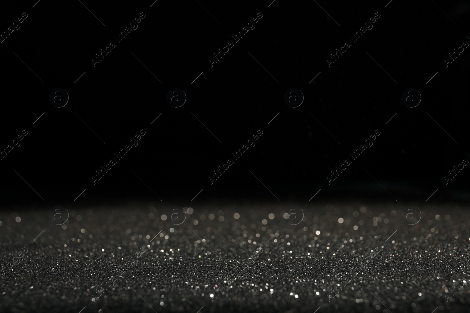 Photo of Shiny grey glitter on black background, space for text. Bokeh effect