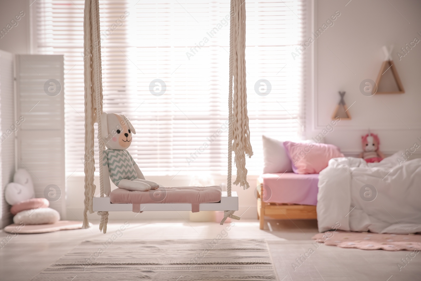 Photo of Beautiful swing with toy dog in room. Stylish interior design