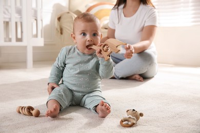 Photo of Cute baby girl playing with wooden toys and mother on floor at home