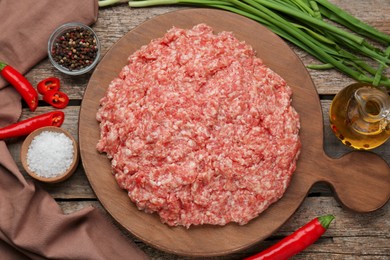 Board with raw fresh minced meat and ingredients on wooden table, flat lay