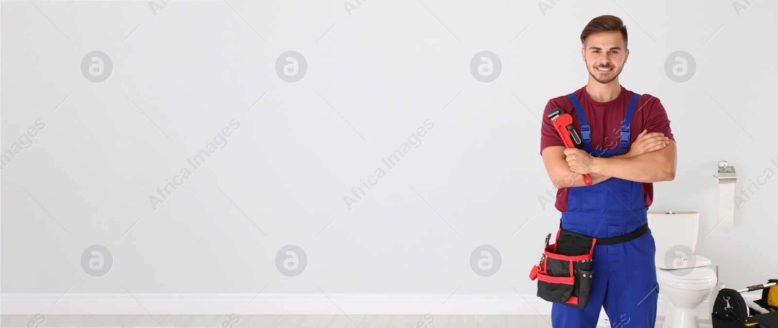 Image of Young man with plumber wrench and toilet bowl on background, space for text. Banner design