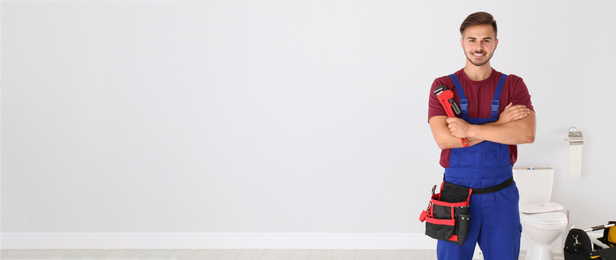 Image of Young man with plumber wrench and toilet bowl on background, space for text. Banner design