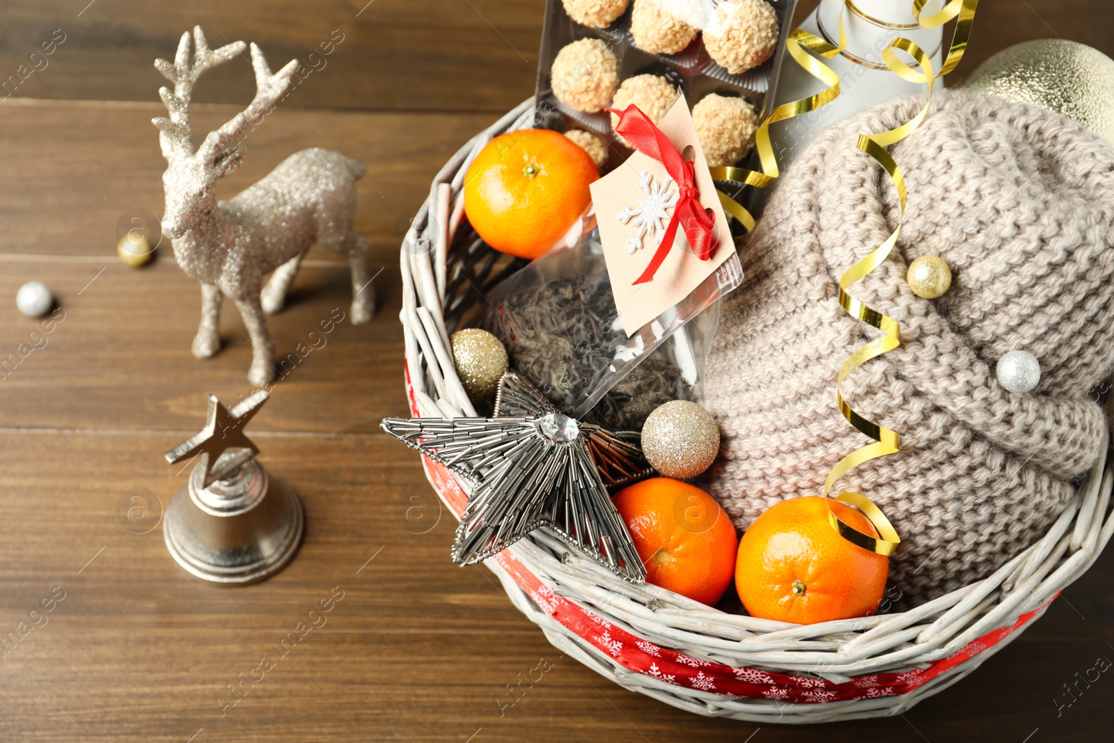 Photo of Wicker basket with gift set and Christmas decor on wooden table