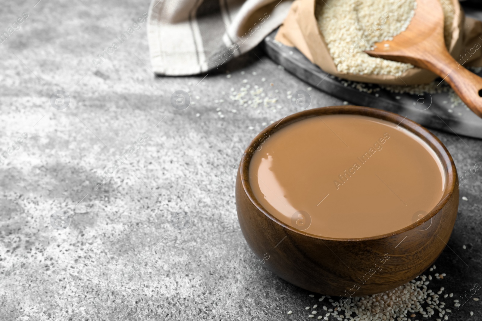 Photo of Tasty sesame paste in bowl on grey table, space for text