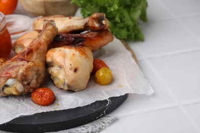 Photo of Roasted chicken drumsticks, tomatoes and marinade on white tiled table. Space for text