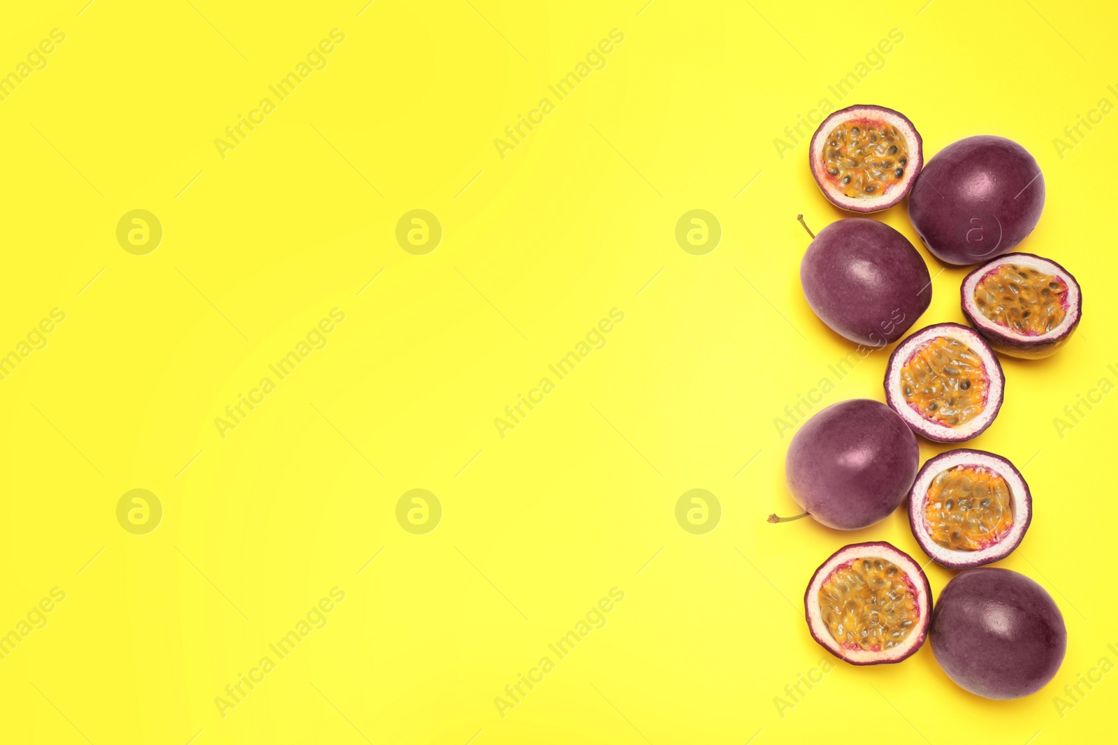 Photo of Fresh ripe passion fruits (maracuyas) on yellow background, flat lay. Space for text