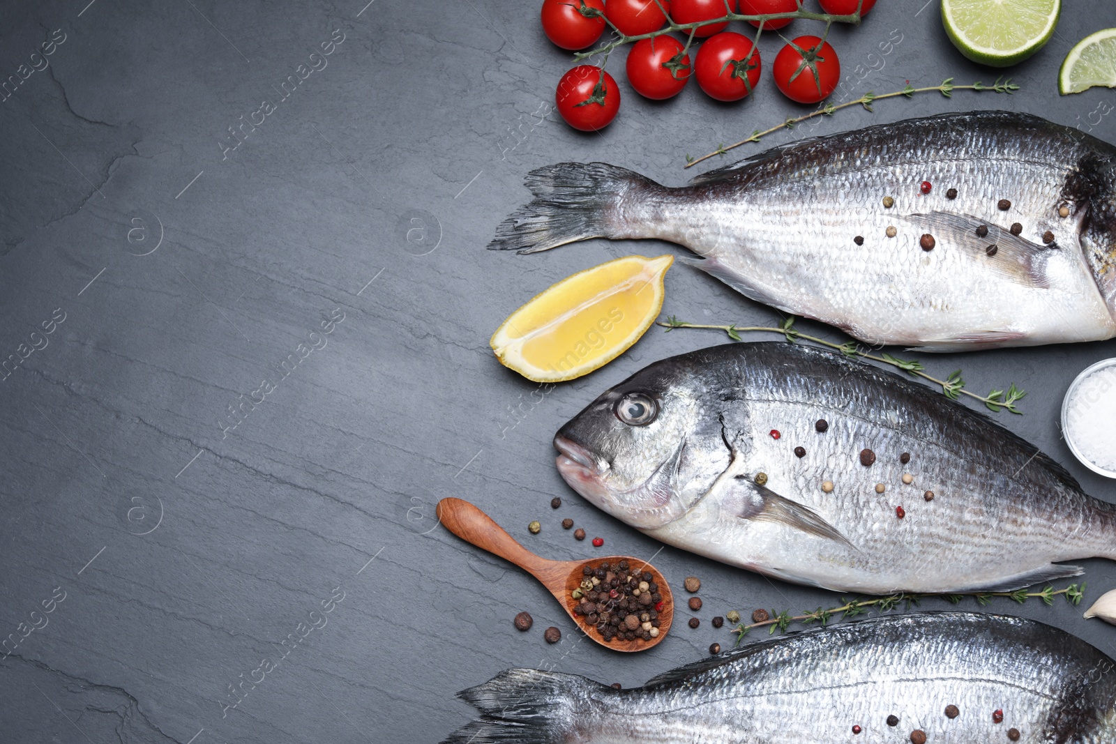 Photo of Flat lay composition with fresh raw dorado fish and ingredients on black table, space for text