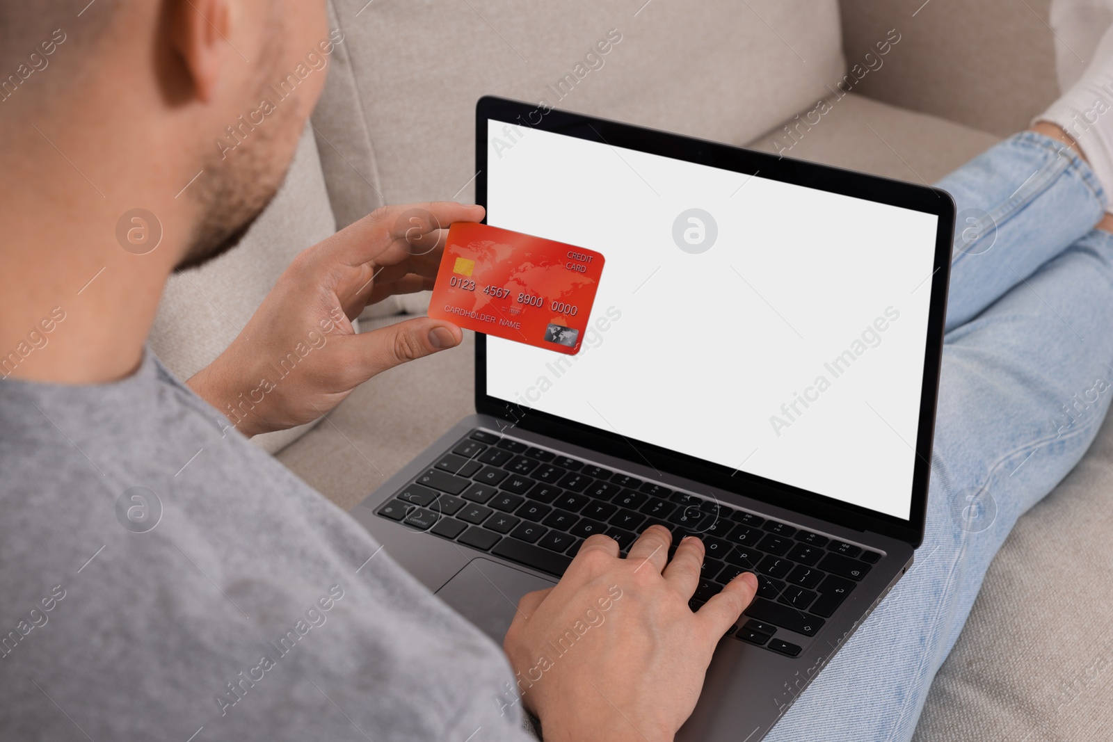 Photo of Man with credit card using laptop for online shopping on sofa, closeup