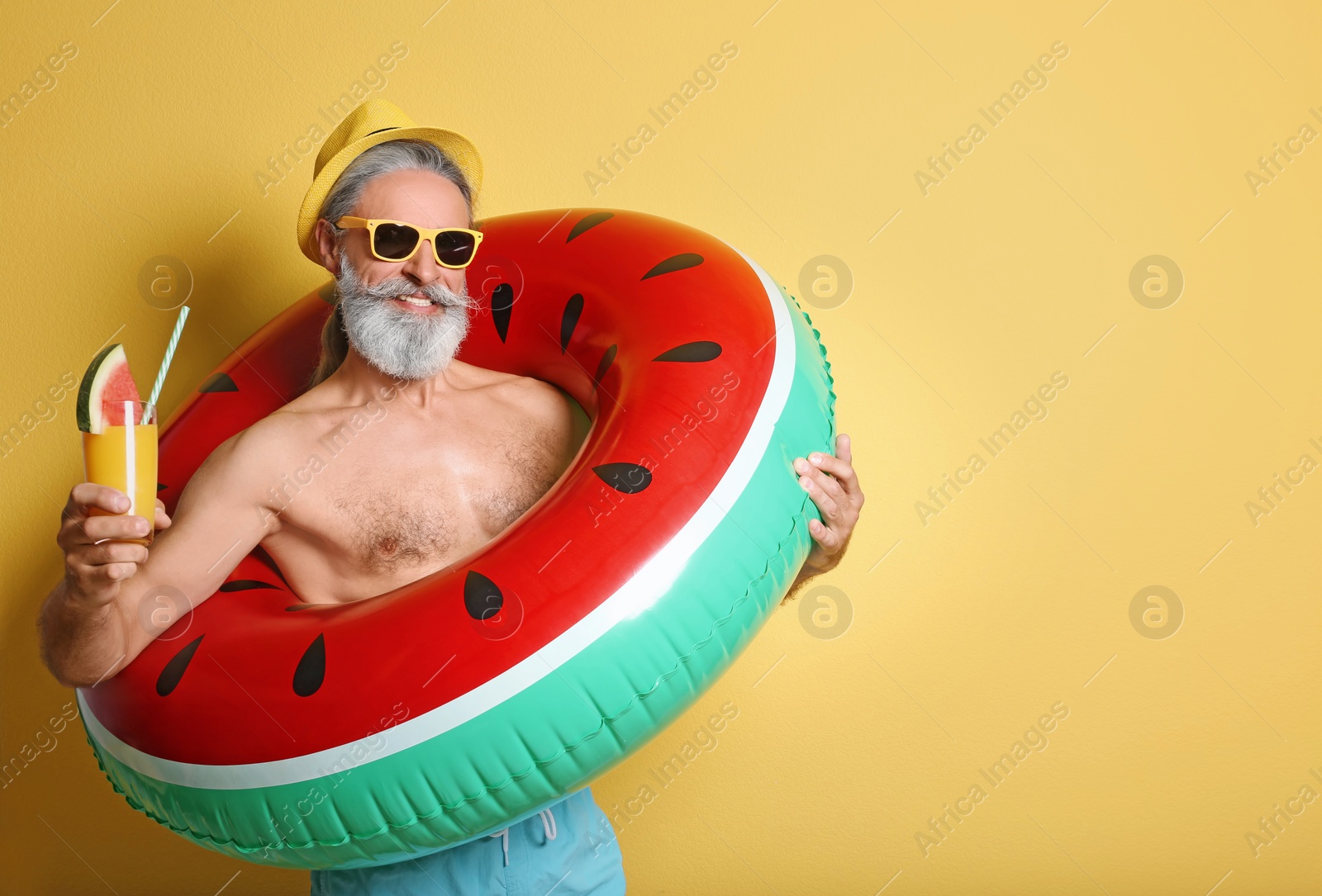 Photo of Shirtless man with inflatable ring and glass of cocktail on color background